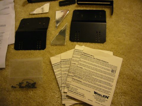 2000 Ford Crown Victoria - Various metal brackets, reflective pieces, and installation instructions are laid out on a carpeted surface.