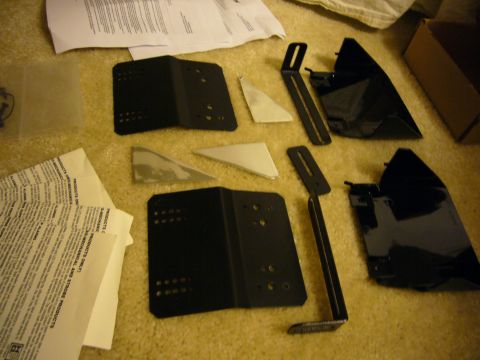 2000 Ford Crown Victoria - A collection of vehicle parts and documentation are spread out on a carpeted floor.