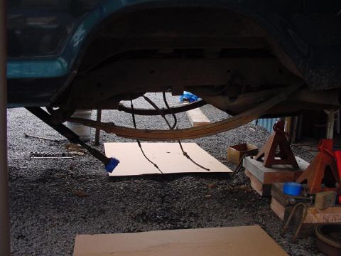 1979 Ford Bronco - The rear suspension system of a vehicle is visible, supported by jack stands for maintenance.