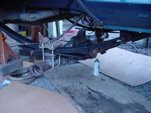 1979 Ford Bronco - Close-up view of a vehicle's rear axle and leaf spring assembly, with a spray can nearby.