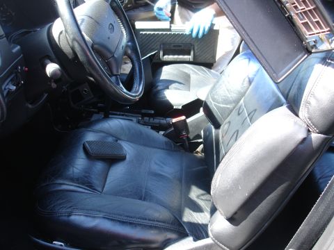 1993 Ford Taurus - Interior view of black leather seats and steering wheel, with a person in blue gloves visible in the background.