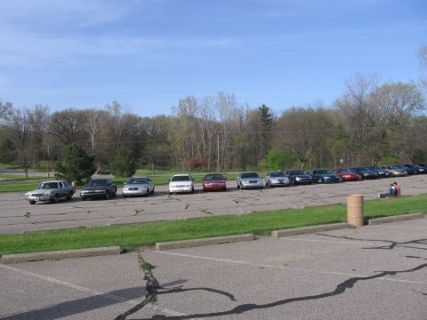 1988 Mercury Grand Marquis - A row of sedans, including a silver 1988 Mercury Grand Marquis, are parked in an outdoor lot under a blue sky.