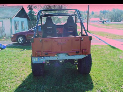 1954 Jeep CJ5 - Rear view of an orange 1954 Jeep CJ5, a roll cage and aftermarket seats.