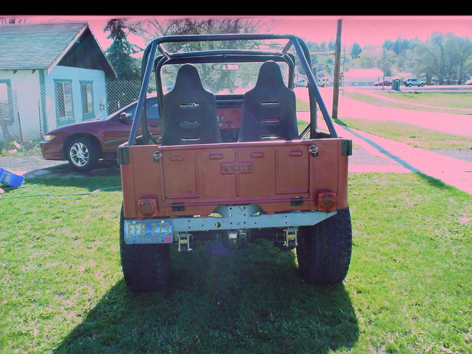 1954 Jeep CJ5 rear view with roll cage and racing seats. Willys logo visible on tailgate