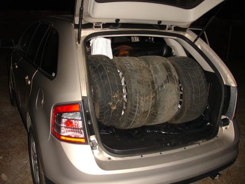 1993 Ford Taurus - Three tires are stored in the cargo area of a tan SUV.