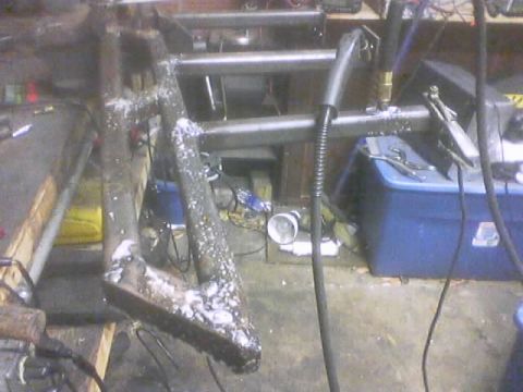 1989 Ford Bronco - Rock sliders are being welded in a workshop environment, with tools and equipment visible in the background.