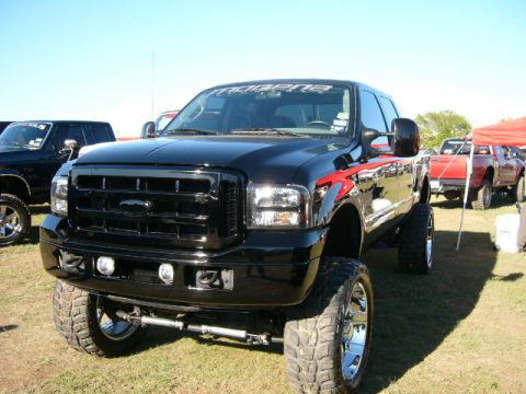 1978 Ford Bronco - Lifted black Ford F-250 truck with custom graphics and large tires at an outdoor event.