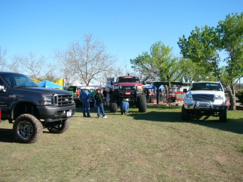 1978 Ford Bronco - Multiple custom trucks are displayed outdoors with spectators milling about.