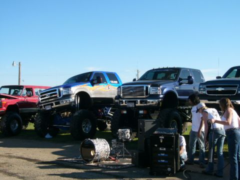 1978 Ford Bronco - Several lifted trucks are on display, with musical equipment set up nearby.