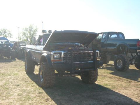 1978 Ford Bronco - A lifted 1979 Ford pickup truck is shown with its hood open, parked next to another modified truck.