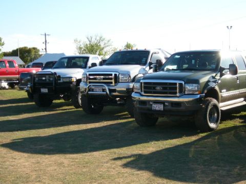 1978 Ford Bronco - Several Ford trucks are parked on a grassy field under a clear sky.