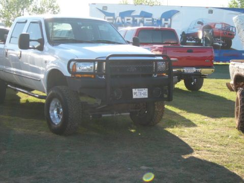 1978 Ford Bronco - A white Ford F-250 Super Duty pickup truck is parked at an outdoor event, with other vehicles visible in the background.