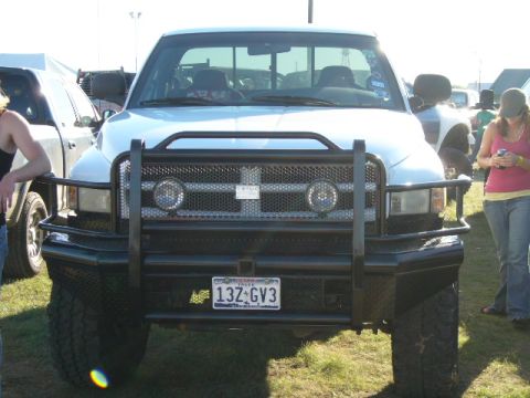 1978 Ford Bronco - Truck with brush guard and off-road tires parked on grass. Another vehicle is visible to the left.