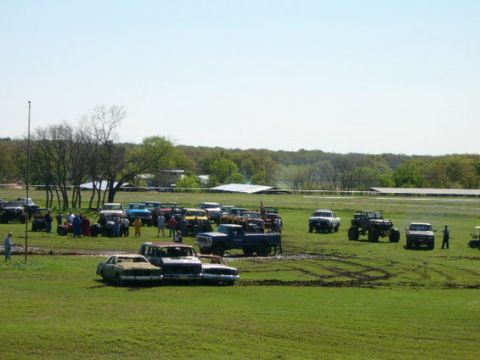 1978 Ford Bronco - A gathering of various vehicles in an open field, with trees and buildings in the background.