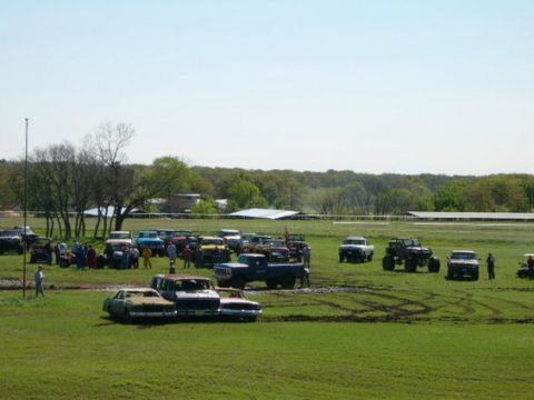 1978 Ford Bronco - A collection of vehicles, including trucks and cars, are parked in a grassy area with evidence of off-road activity.