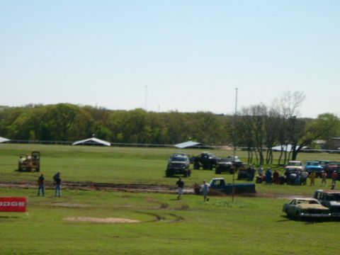 1978 Ford Bronco - A collection of modified vehicles are parked on a field under a clear sky.