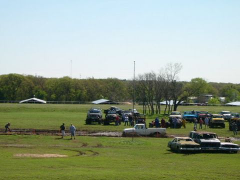1978 Ford Bronco - Multiple trucks and SUVs are stuck in the mud at an outdoor event.