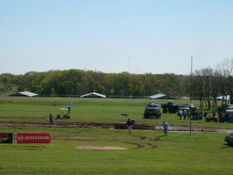 1978 Ford Bronco - Off-road vehicles and spectators gather at a muddy event, with a Dodge banner visible in the foreground.