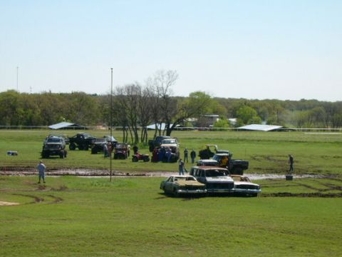 1978 Ford Bronco - A gathering of various vehicles, including trucks and cars, in a muddy outdoor area.