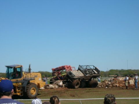 1978 Ford Bronco - Several off-road vehicles appear stuck in a muddy area, with a yellow loader nearby.