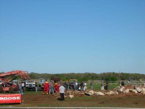 1978 Ford Bronco - A group of people and several off-road vehicles are gathered on a muddy field, with a red Dodge banner visible in the foreground.