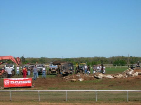 1978 Ford Bronco - Multiple off-road vehicles are present at an event, with one vehicle overturned on the dirt track.