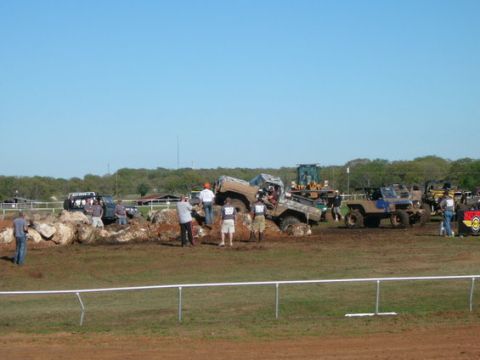 1978 Ford Bronco - Several off-road vehicles are engaged in an obstacle course, with one vehicle stuck on rocks.
