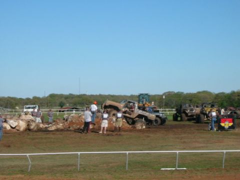 1978 Ford Bronco - Several off-road vehicles are engaged in an obstacle course event, with spectators observing the action on a sunny day.
