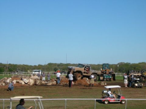 1978 Ford Bronco - A modified truck navigates a challenging obstacle course with spectators and support vehicles nearby.