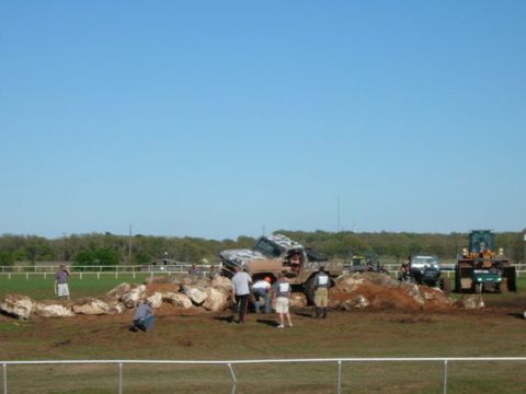 1978 Ford Bronco - A group of people are gathered around a modified off-road vehicle attempting to traverse a rocky terrain.