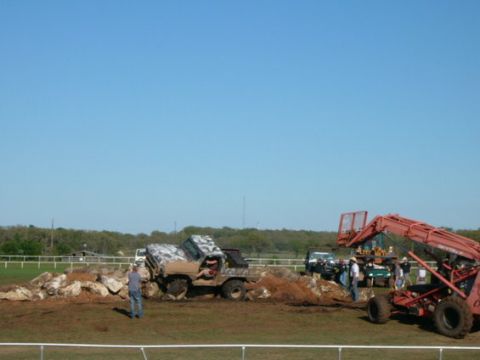 1978 Ford Bronco - Several off-road vehicles are gathered on a dirt and rock obstacle course under a clear blue sky.