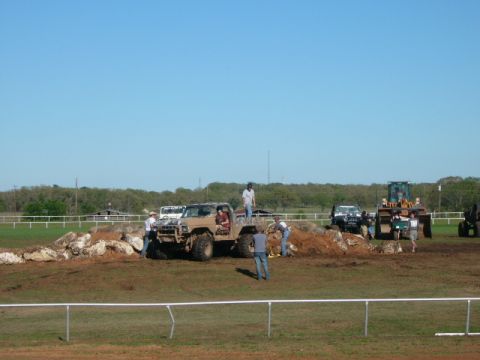 1978 Ford Bronco - Several off-road vehicles and a tractor are gathered on a dirt course, with people observing and interacting with the vehicles.