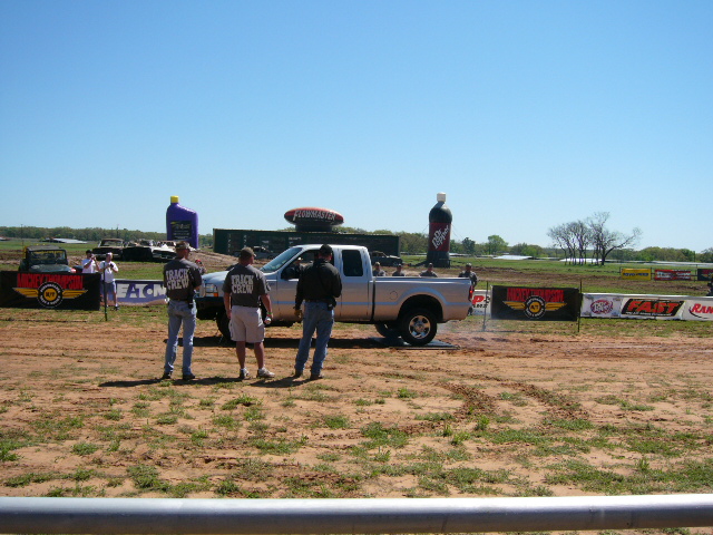 Silver pickup truck doing a burnout with track crew members watching