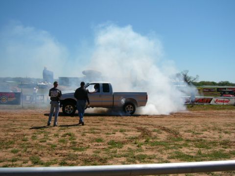 1978 Ford Bronco - Pickup truck performing a burnout, generating significant smoke. Two observers are present.