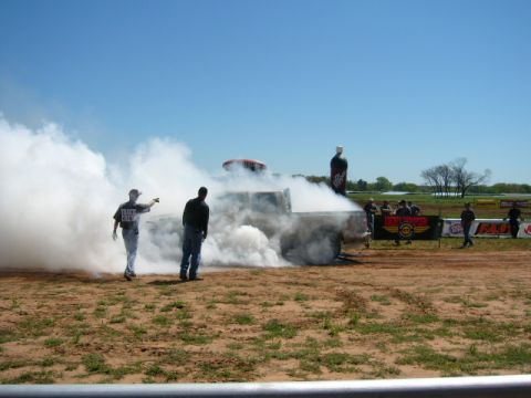 1978 Ford Bronco - A truck performs a burnout, creating a large cloud of smoke on a sunny day at an outdoor event.