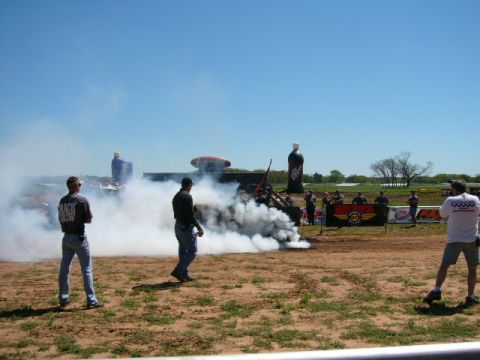 1978 Ford Bronco - A drag car performs a burnout, kicking up a massive cloud of smoke during an outdoor event.