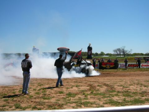 1978 Ford Bronco - A modified Jeep performs a burnout, kicking up a large cloud of smoke, under a clear blue sky.