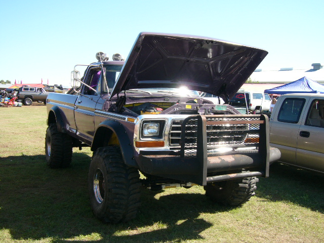 Purple and silver lifted 1970s Ford pickup with hood up and grille guard on grass