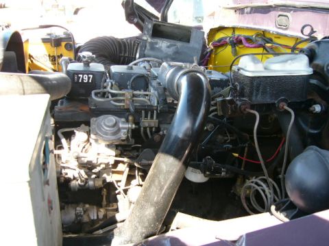 1978 Ford Bronco - Close-up into the engine bay of a purple-painted truck showing a diesel inline engine with injection lines, fuel filter housing and a large…