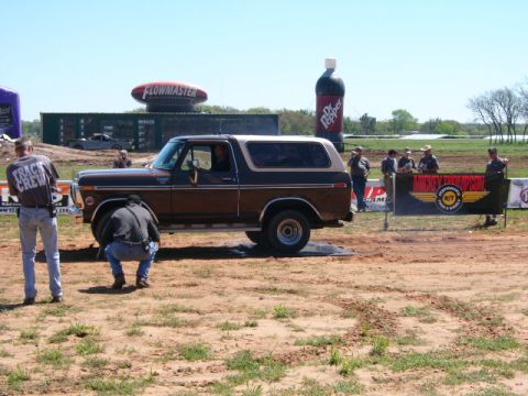 1978 Ford Bronco - A 1978 Ford Bronco performs a burnout at an outdoor event with spectators and advertising banners.