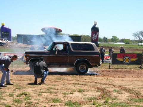 1978 Ford Bronco - A 1978 Ford Bronco performs a burnout at an outdoor event with spectators and large inflatable advertisements.