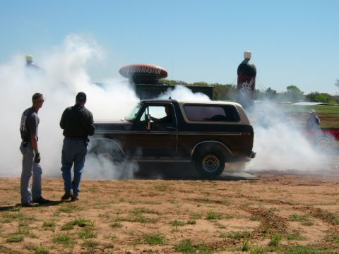 1978 Ford Bronco - A 1978 Ford Bronco performs a burnout, kicking up a large cloud of smoke as two onlookers observe.