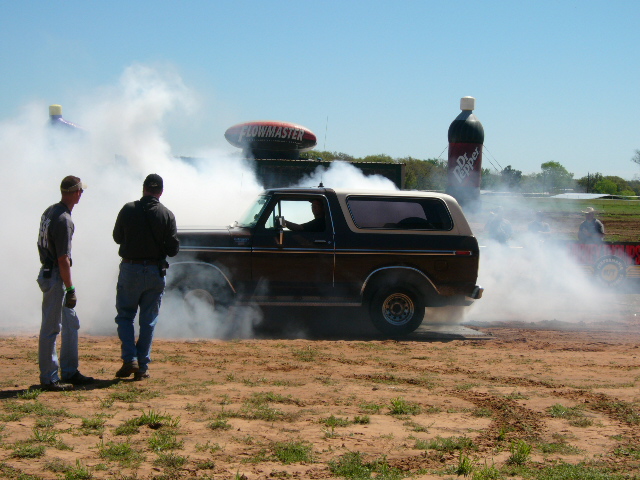 Brown 1978 Ford Bronco doing a burnout with two men watching