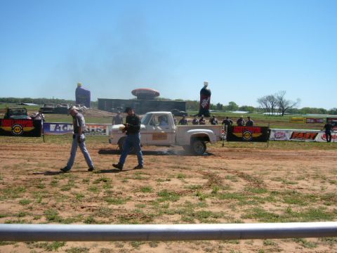 1978 Ford Bronco - A white pickup truck performs a burnout on a dirt track under a clear blue sky.