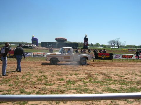 1978 Ford Bronco - A white 1978 Ford F-150 Stepside performs a burnout on a dirt track with spectators in the background.