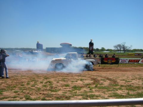 1978 Ford Bronco - A white pickup truck performs a burnout, kicking up a large cloud of smoke during an event.