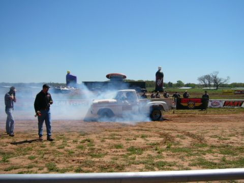 1978 Ford Bronco - Pickup truck performing a burnout on a dirt track with spectators in the background.