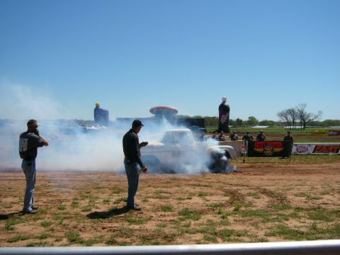 1978 Ford Bronco - A pickup truck performs a burnout, generating a large cloud of smoke under a clear blue sky.