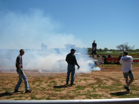 1978 Ford Bronco - A white pickup truck performs a burnout, creating a cloud of smoke as onlookers observe.