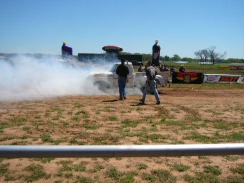 1978 Ford Bronco - A white pickup truck performs a burnout, creating a large cloud of smoke on a sunny day.